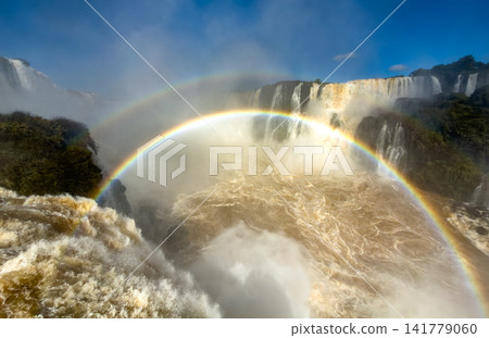 A rainbow arcs brilliantly across the misty basin of Iguazu Falls. A rainbow arcs brilliantly across the misty basin of Iguazu Falls. 141779060