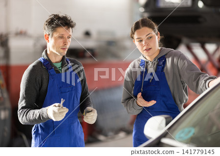 Girl and man auto mechanics talk about algorithm of work, consult with each other Girl and man auto mechanics talk about algorithm of work, consult with each other 141779145