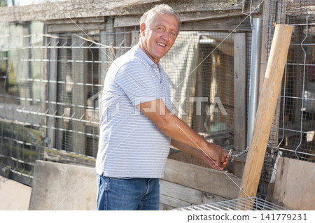 Portrait of an elderly farm owner with a chicken coop in background Portrait of an elderly farm owner with a chicken coop in background 141779231