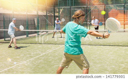 Adult men playing padel against two men Adult men playing padel against two men 141779301