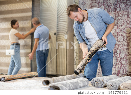 Young man choosing carpet in building store Young man choosing carpet in building store 141779311