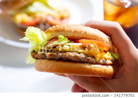 Eating a hamburger, the hands holding the burger Eating a hamburger, the hands holding the burger 141779701