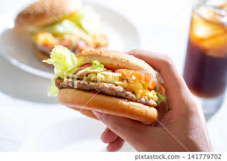 Eating a hamburger, the hands holding the burger Eating a hamburger, the hands holding the burger 141779702