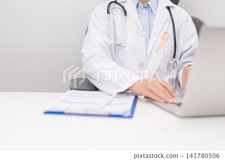 doctor using laptop and report notes on notebook. peach ribbon concept of September Uterine Cancer Awareness month, Endometrial, Gynecologic, Uterus and Ovaries, Endometriosis, June Vaginal cancer doctor using laptop and report notes on notebook. peach ribbon concept of September Uterine Cancer Awareness month, Endometrial, Gynecologic, Uterus and Ovaries, Endometriosis, June Vaginal cancer 141780506