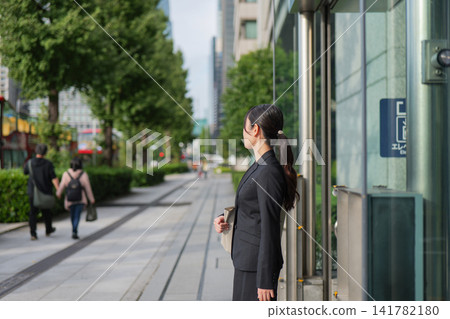 A young businesswoman standing on a street in Marunouchi A young businesswoman standing on a street in Marunouchi 141782180