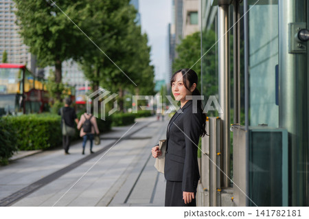 A young businesswoman standing on a street in Marunouchi A young businesswoman standing on a street in Marunouchi 141782181