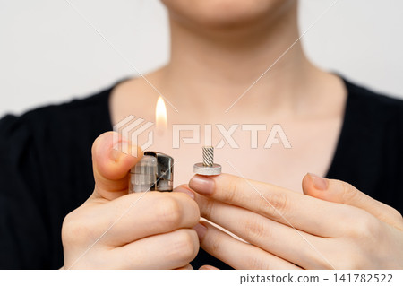 The hand holding the lighter flame close to the moxa base to ignite it. The hand holding the lighter flame close to the moxa base to ignite it. 141782522