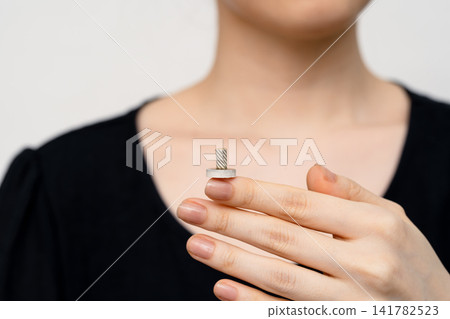 A woman in black clothing holding an unlit moxa cone. A woman in black clothing holding an unlit moxa cone. 141782523