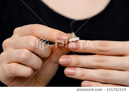 一名女子用雙手手指尖握著燃燒的艾炷。 一名女子用雙手手指尖握著燃燒的艾炷。 141782524