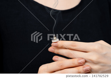 一名身穿黑衣的女子將艾錐放在手背上。 一名身穿黑衣的女子將艾錐放在手背上。 141782529