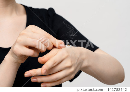A woman's arm and upper body, showing moxibustion on the back of her hand with her fingertips. A woman's arm and upper body, showing moxibustion on the back of her hand with her fingertips. 141782542