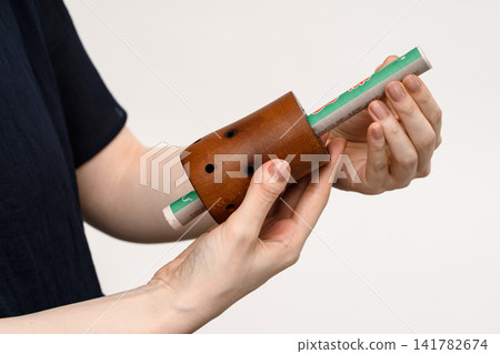 一名女子用雙手調整木製艾灸器中的艾條。 一名女子用雙手調整木製艾灸器中的艾條。 141782674