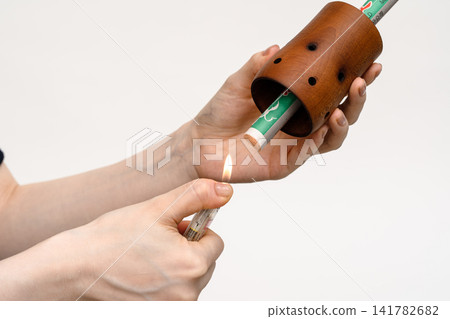 一名女子用打火機點燃放在艾灸器中的艾條。 一名女子用打火機點燃放在艾灸器中的艾條。 141782682