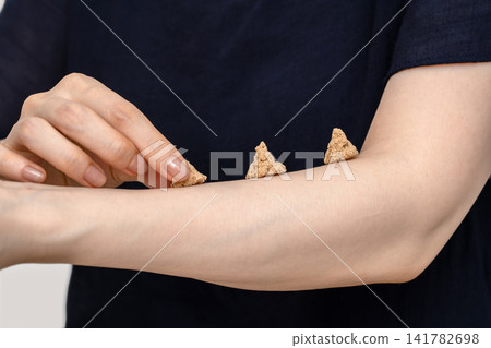 一名女子將手指放在前臂上並排擺放的三個艾灸穴位上。 一名女子將手指放在前臂上並排擺放的三個艾灸穴位上。 141782698