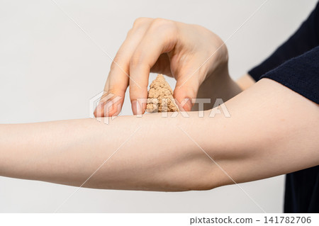 A woman's hand placing a large cone-shaped moxa on her forearm. A woman's hand placing a large cone-shaped moxa on her forearm. 141782706