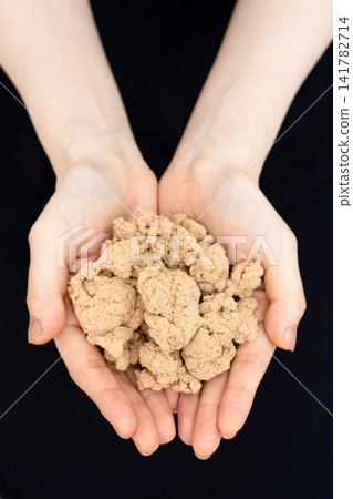 A woman's hands cupping dried moxa in both palms. A woman's hands cupping dried moxa in both palms. 141782714
