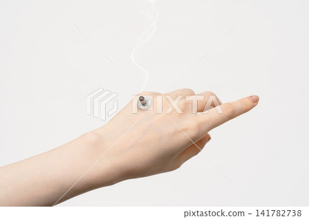 A burning moxibustion pedestal placed on the back of a woman's hand against a white background. A burning moxibustion pedestal placed on the back of a woman's hand against a white background. 141782738