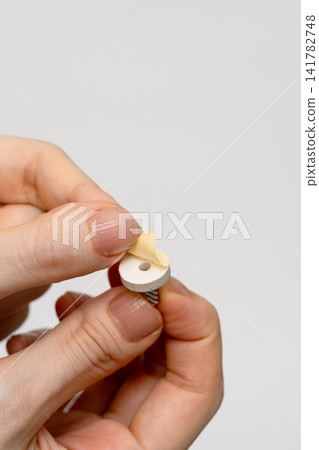 一名女子用手指剝開艾灸錐背面的保護膜。 一名女子用手指剝開艾灸錐背面的保護膜。 141782748