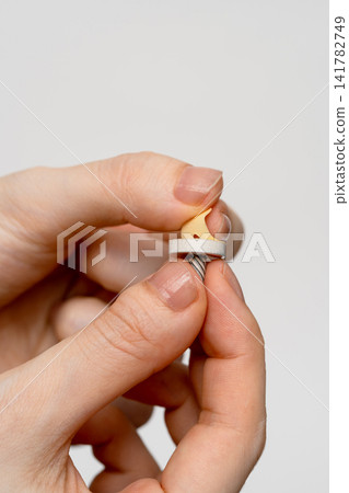 A woman's fingers peeling off the protective seal from the back of the moxa cone. A woman's fingers peeling off the protective seal from the back of the moxa cone. 141782749
