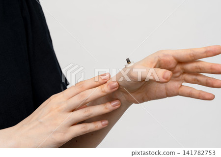 A used moxa cone placed on the inside of the wrist and a woman's hand A used moxa cone placed on the inside of the wrist and a woman's hand 141782753