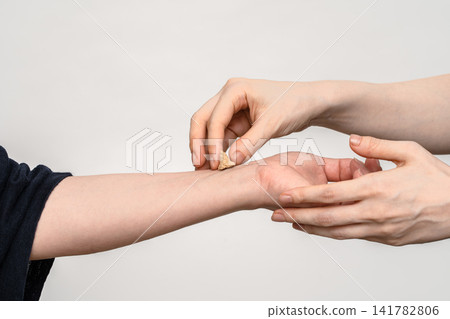 兩位物理治療師正在進行治療,一位正在為另一位物理治療師的前臂上紮艾灸。 兩位物理治療師正在進行治療,一位正在為另一位物理治療師的前臂上紮艾灸。 141782806
