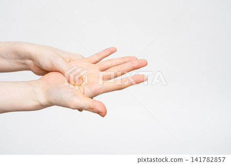 A woman pressing the pressure point in the center of her palm with her thumbs on both hands. A woman pressing the pressure point in the center of her palm with her thumbs on both hands. 141782857