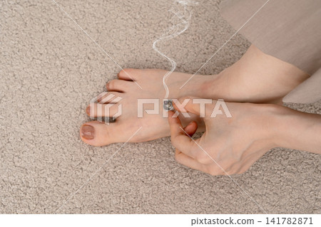 手指托著放在女人腳背上的艾錐,艾錐正冒著煙。 手指托著放在女人腳背上的艾錐,艾錐正冒著煙。 141782871