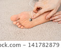 A self-care treatment involving placing fingers on a moxibustion base on the soles of a woman's feet. 141782879