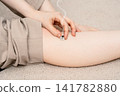 A woman places her hand on a pedestal-type moxibustion device that is emitting smoke on her shin. 141782880
