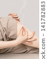 Vertical heat therapy using a moxibustion base on a woman's knee, supported by both hands. 141782883