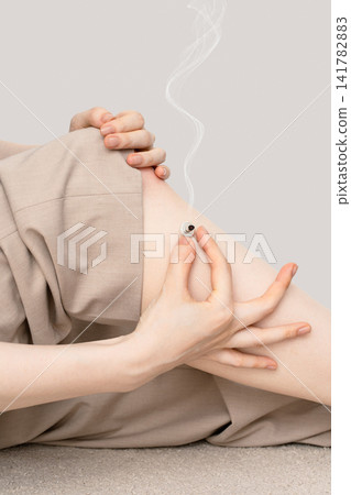Vertical heat therapy using a moxibustion base on a woman's knee, supported by both hands. Vertical heat therapy using a moxibustion base on a woman's knee, supported by both hands. 141782883