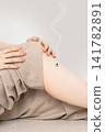 A woman's bent knees are used to place a smoky moxibustion device on a base, with both hands supporting it. 141782891