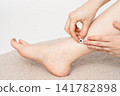 A woman's legs and feet, with moxibustion applied to the ankle using both hands. 141782898