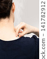 A woman with smoke rising from a moxa cone at the base of her neck and shoulder. 141782912