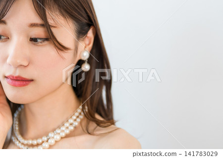 一位年輕亞洲女性的脖子上戴著珍珠項鍊和耳環。 141783029