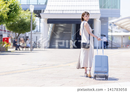 A woman carrying a suitcase heads towards the train station. A woman carrying a suitcase heads towards the train station. 141783058