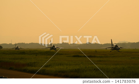 A Japan Air Self-Defense Force T-4 trainer aircraft taxiing at dusk. A Japan Air Self-Defense Force T-4 trainer aircraft taxiing at dusk. 141783076