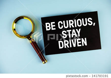 Be Curious, Stay Driven text with Magnifying glass on blue background Be Curious, Stay Driven text with Magnifying glass on blue background 141783191