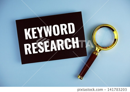 Keyword Research text written on paper card with magnifying glass top view on blue background Keyword Research text written on paper card with magnifying glass top view on blue background 141783203