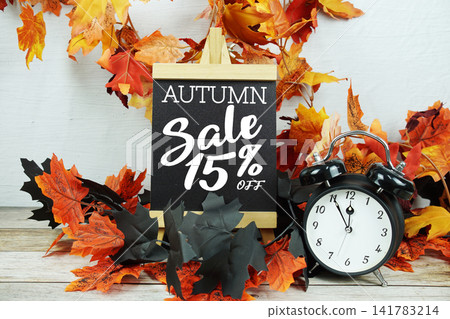 Autumn Sale 15% text with alarm clock and maple leaf decoration on wooden background 141783214