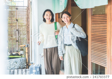 兩名面帶微笑的女子來到溫泉旅館門口。 兩名面帶微笑的女子來到溫泉旅館門口。 141783377