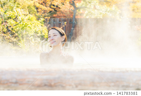 A woman relaxing both physically and mentally while soaking in the open-air bath. A woman relaxing both physically and mentally while soaking in the open-air bath. 141783381