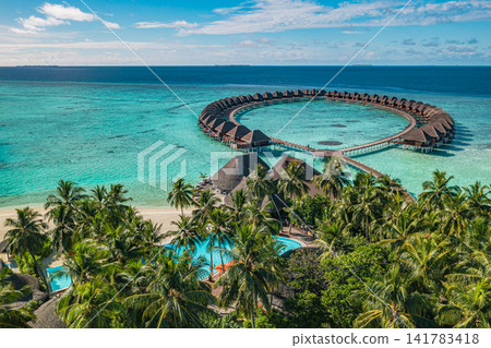 Breathtaking overhead lagoon circular overwater villas ringed by turquoise water Maldives luxury resort deep blue sea. Perfect summer vacation travel landscape paradise. Luxury honeymoon getaway scene Breathtaking overhead lagoon circular overwater villas ringed by turquoise water Maldives luxury resort deep blue sea. Perfect summer vacation travel landscape paradise. Luxury honeymoon getaway scene 141783418