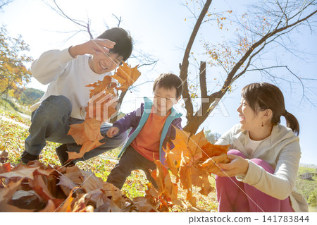 一家三口在落葉環繞的公園玩耍。 141783844