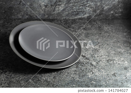 Empty round black plates on a black stone background. Empty round black plates on a black stone background. 141784027