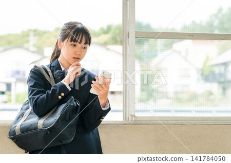 Elementary, middle, and high school girls using smartphones in the school hallway (thinking, worrying, hesitating, troubled) Elementary, middle, and high school girls using smartphones in the school hallway (thinking, worrying, hesitating, troubled) 141784050