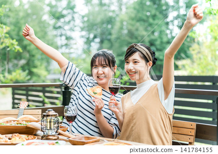 年輕女性在露臺上享受美食、燒烤、家庭聚會以及與朋友一起體驗豪華露營。 141784155