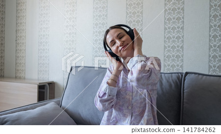 Young mother enjoying music with headphones relaxing at home Young mother enjoying music with headphones relaxing at home 141784262