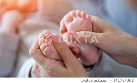 Mother gently holding baby feet symbolizing new life Mother gently holding baby feet symbolizing new life 141784308
