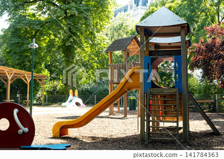 Childrens playground with slide in a green city park on a sunny summer day Childrens playground with slide in a green city park on a sunny summer day 141784363